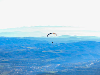 Person paragliding over mountain against the sky