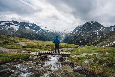 Rear view of person walking on snowcapped mountain against sky