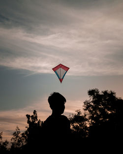 Silhouette boy standing against sky during sunset