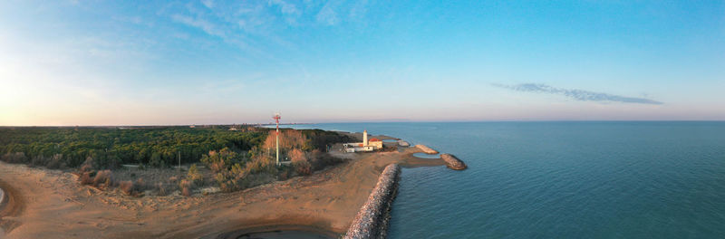 Bibione lighthouse from above at sunset in a panoramic aerial view	with sea and blue sky