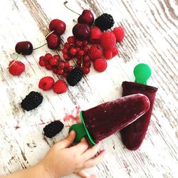 Directly above shot of hand holding berries on table