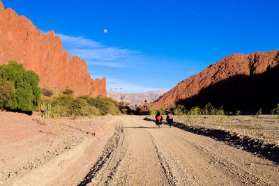 People walking on dirt road along landscape