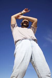 Low section of woman standing against clear blue sky