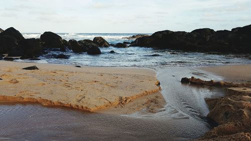 Close-up of waves splashing on beach against sky