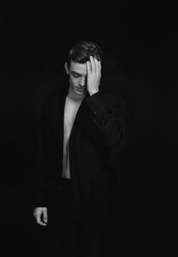 Young man standing against black background