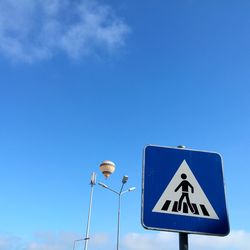 Low angle view of road sign against blue sky