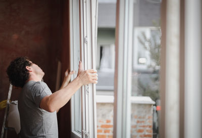 A young man installs a window frame with glass.