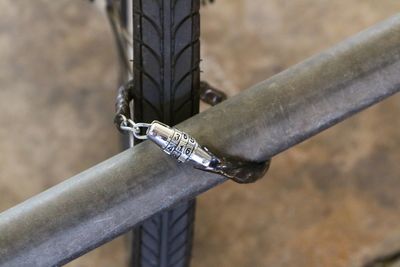 Cropped image of bicycle attached with lock on railing