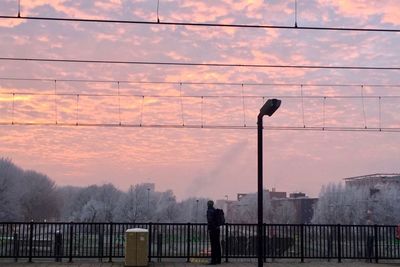 Silhouette man standing by railing against sky