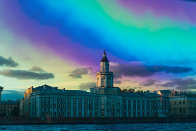 View of buildings against rainbow in sky at sunset