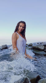 Young woman standing on beach against clear sky