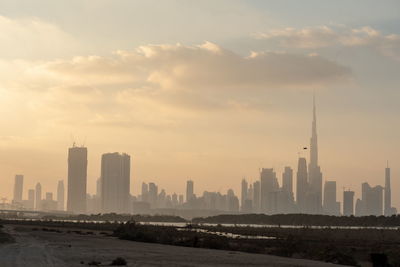 Modern buildings in city against sky during sunset