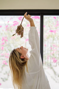 Woman wearing white dress dancing with a protea flower