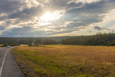 Empty road amidst field against sky