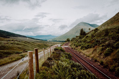 View of railroad tracks by mountain against sky