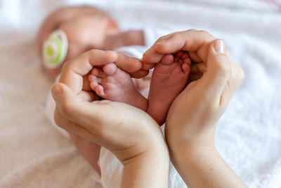 Low section of baby lying on bed