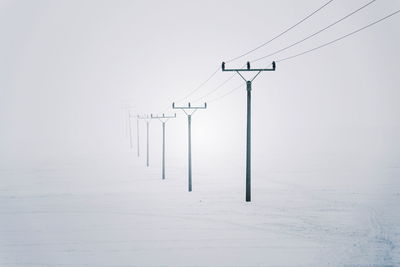 Electricity pylons from distribution power station disappearing in deep fog