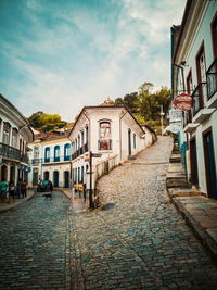 Footpath amidst houses against sky in city