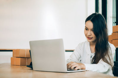 Young woman using phone while sitting on table