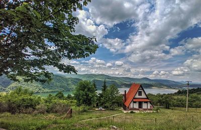 House on field by trees against sky