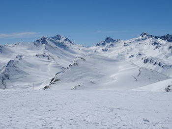 Scenic view of snow covered mountains against blue sky