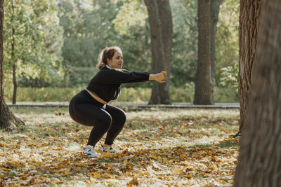 Young woman squatting in park