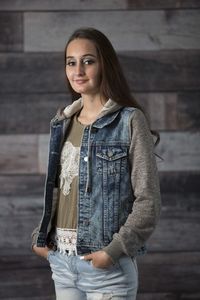 Portrait of young woman standing against wall