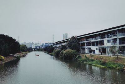 Canal amidst buildings against clear sky