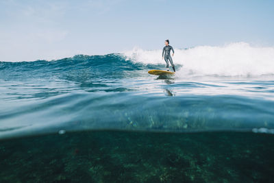 Split image of a female surfer in wetsuit surfing a small wave