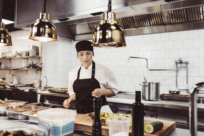 Kvinnlig kock förbereder ingredienser i restaurangkök