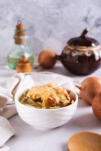 Homemade onion soup with croutons and cheese in a bowl on the table vertical view