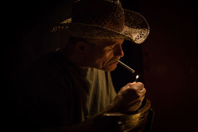 Senior man smoking cigarette in darkroom