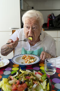 Old lady eating alone healthy food at home