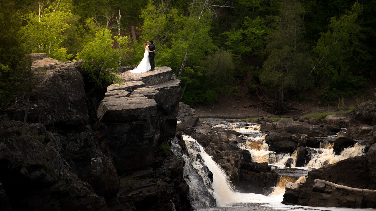 WOMAN STANDING ON ROCK BY RIVER