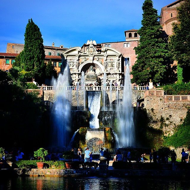 fountain, water, architecture, built structure, building exterior, spraying, motion, splashing, statue, famous place, tree, long exposure, travel destinations, sculpture, tourism, flowing water, waterfront, travel, incidental people, waterfall