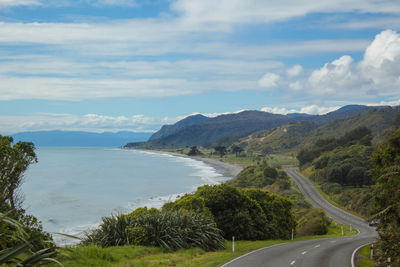 Scenic view of road by sea against sky