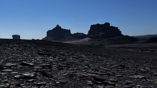 Rock formations on landscape against clear blue sky