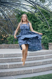 Portrait of happy young woman jumping on steps at park
