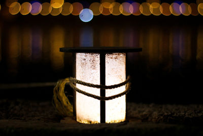 Close-up of rope tied to illuminated bollard by river