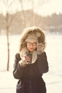 Portrait of young woman holding disposable cup during winter