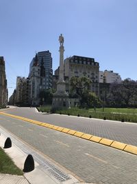 Statue in city against clear sky