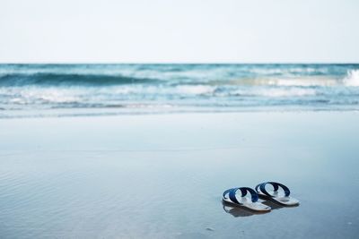 Flip-flops on shore against clear sky