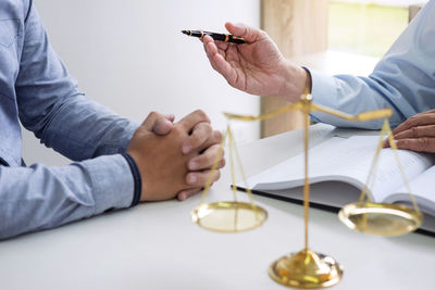 Midsection of lawyer discussing with client at desk in office