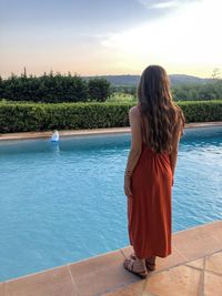 Rear view of woman standing by swimming pool