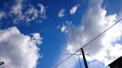 Low angle view of electricity pylon against blue sky