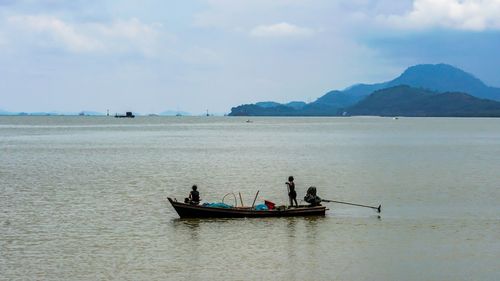 People in boat on sea against sky