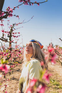 Young woman looking away while sitting on tree