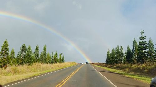 Rainbow over road against sky