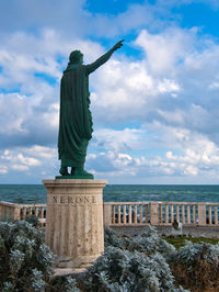 Statue by sea against sky