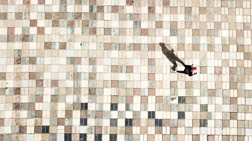 High angle view of man walking on tiled floor during sunny day